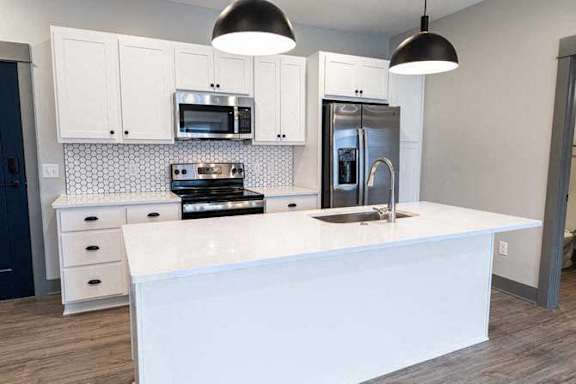 A modern kitchen with white countertops and stainless steel appliances.