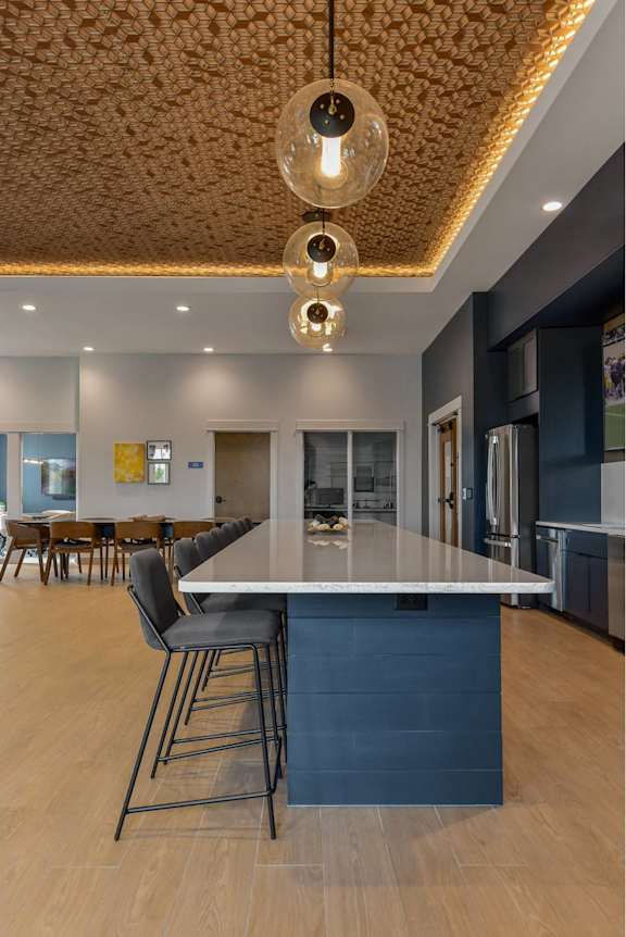 A modern kitchen with a large island and pendant lights.