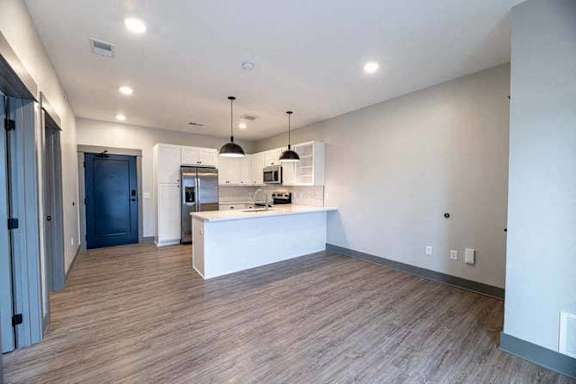 A modern kitchen with a white island and pendant lights.