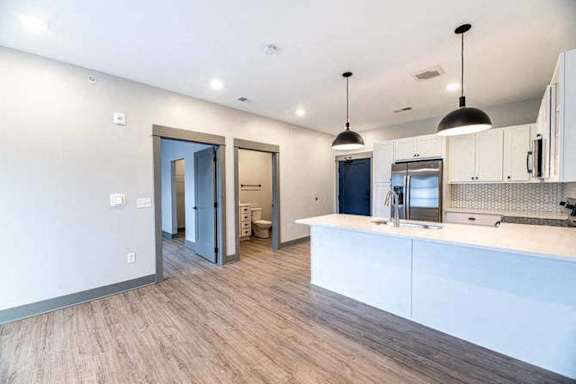 A modern kitchen with a white countertop and wooden flooring.