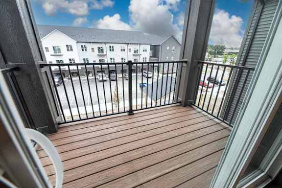 A balcony with a black railing and a white chair.