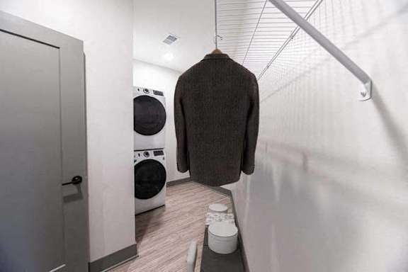 A brown sweater hanging on a rack in a laundry room.