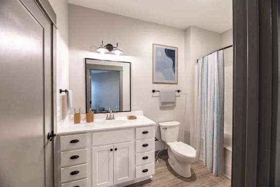 A bathroom with a toilet, sink, and mirror.