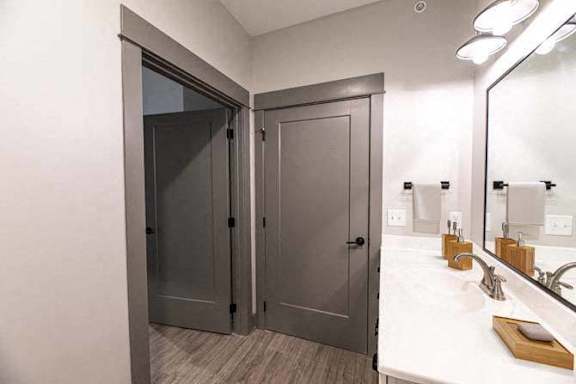 A bathroom with a white counter top and a large mirror.