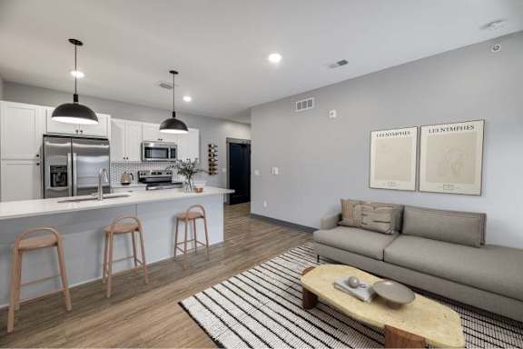 A modern kitchen with a bar area and a grey sofa.
