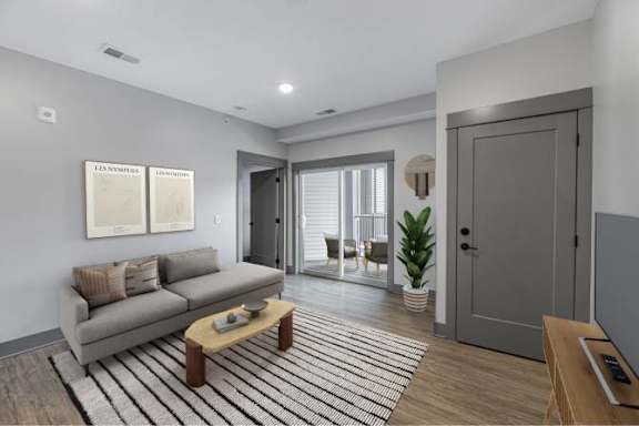 A modern living room with a grey couch and a striped rug.