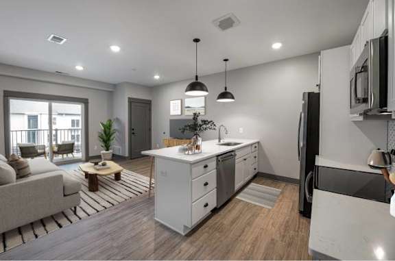 A modern kitchen with white cabinets and a wooden floor.