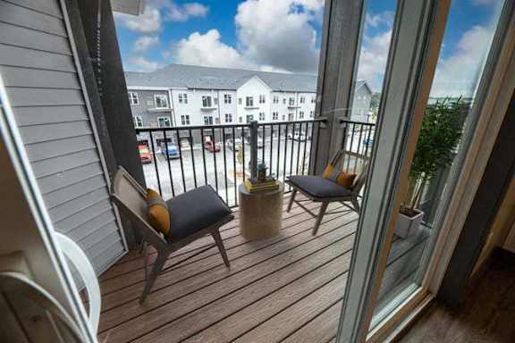 A balcony with two chairs and a table.