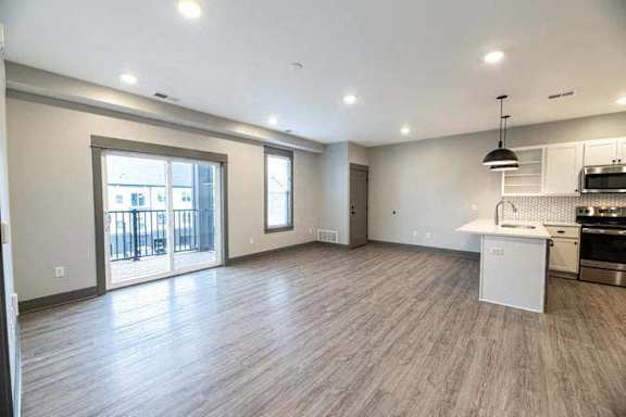 A spacious living room with a kitchen area in the background.