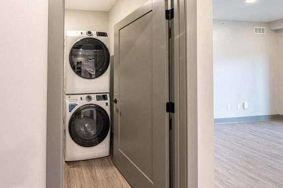 A washer and dryer are in a small, white-walled laundry room.