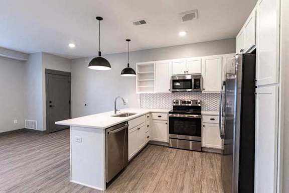 A modern kitchen with white cabinets and stainless steel appliances.