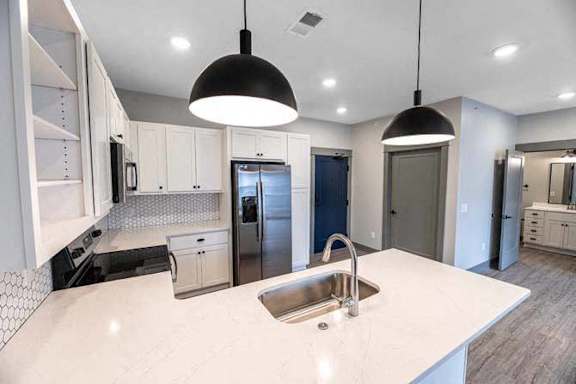 A modern kitchen with a white countertop and a stainless steel sink.