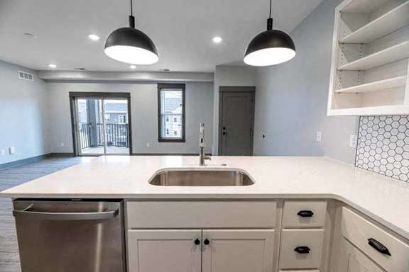 A modern kitchen with a white countertop and stainless steel appliances.