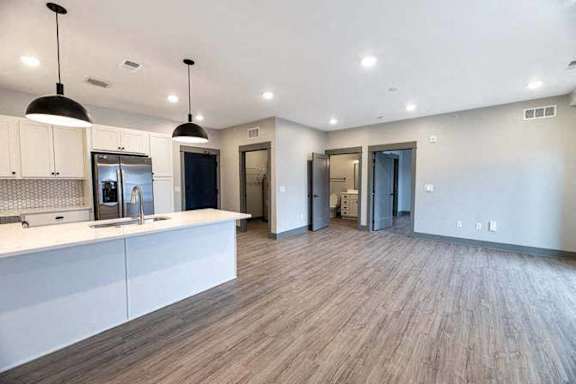 A kitchen with a refrigerator, sink, and cabinets.