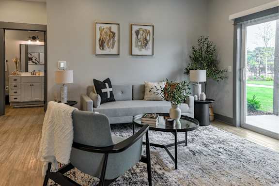 A grey couch with a white throw blanket on it sits in a living room.