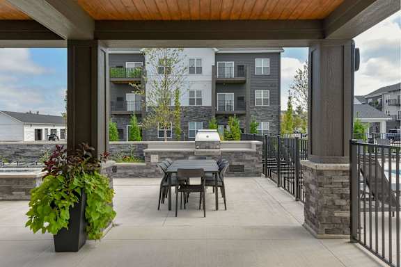 A patio with a table and chairs is surrounded by a black fence.