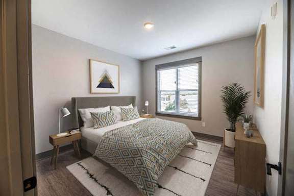 A bedroom with a bed, nightstand, and a window.