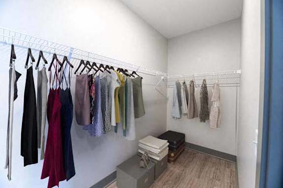 A row of clothes hanging on a rack in a room.