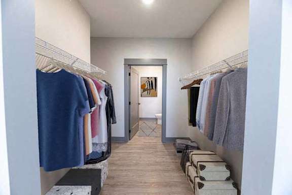 A walk-in closet with clothes hanging on racks and a mirror on the wall.