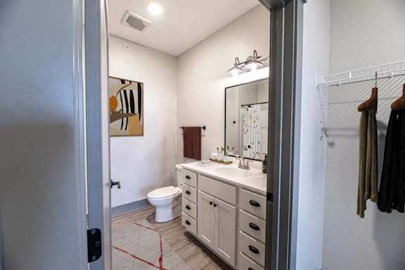 A bathroom with a toilet, sink, and mirror.