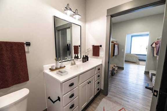 A bathroom with a white vanity and a large mirror.
