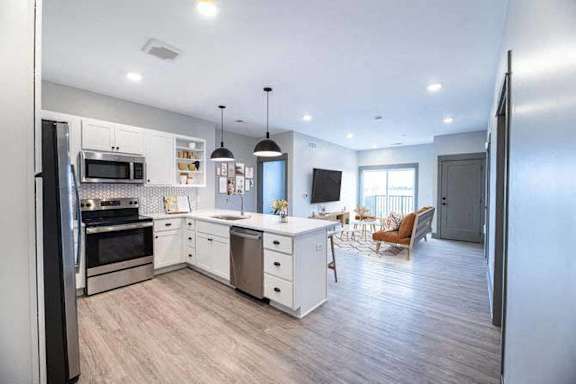 A modern kitchen with white cabinets and stainless steel appliances.