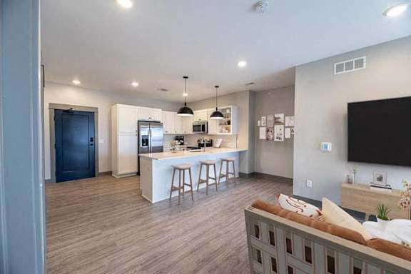 A modern kitchen with a bar area and a living room area with a couch.