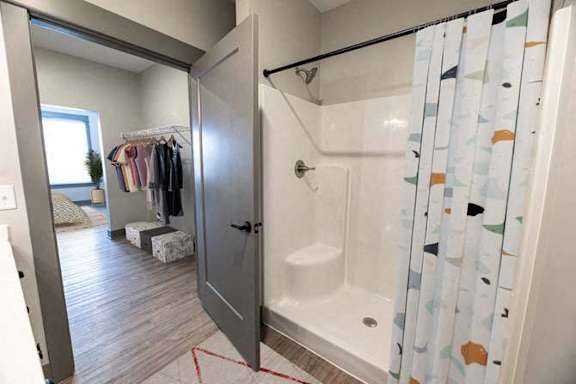 A bathroom with a shower curtain and a wooden floor.