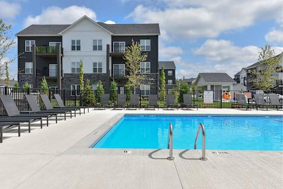 A large swimming pool in front of a multi-story apartment building.