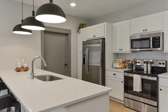 A modern kitchen with a white countertop and stainless steel appliances.