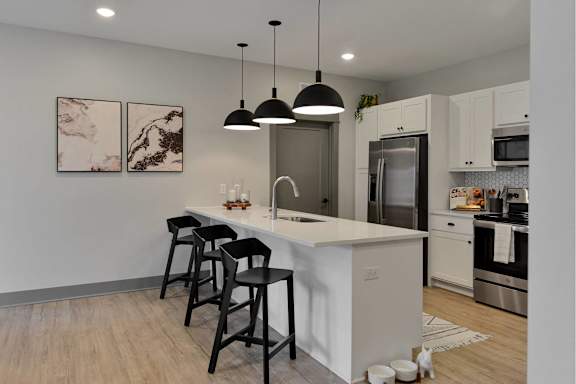 A kitchen with a white island and black bar stools.