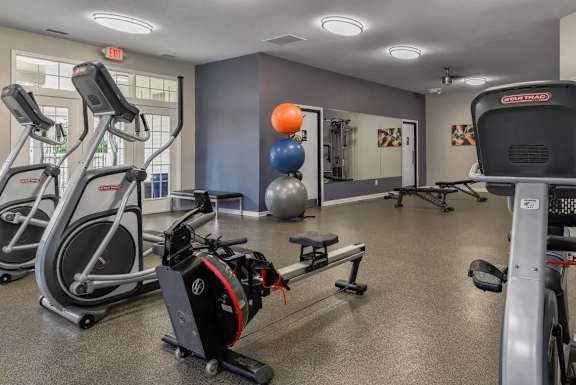 A gym with a variety of equipment including treadmills, exercise balls, and weight machines.