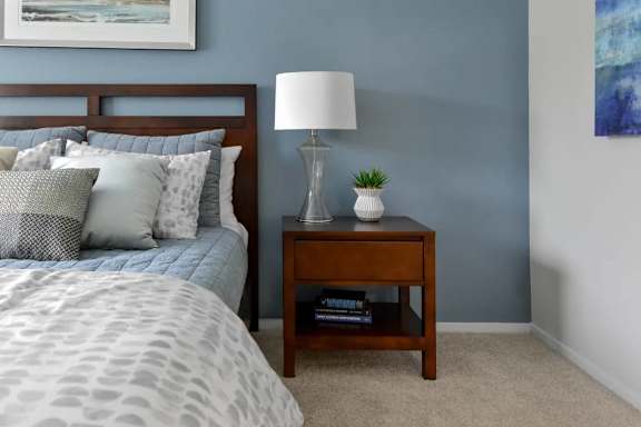 A bedroom with a bed, nightstand, and lamp.