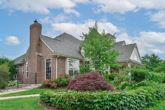 A house with a brick chimney and a well-manicured garden.