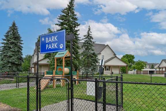 A sign that says Bark Park is in front of a playground.