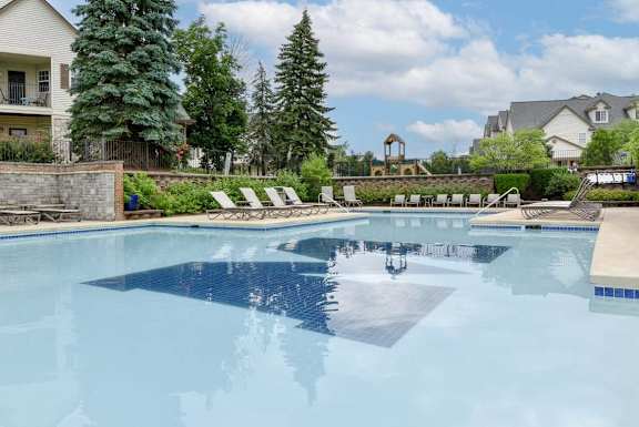 A swimming pool with a stone wall and trees in the background.