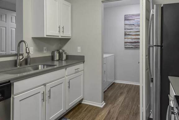 A kitchen with white cabinets and a black refrigerator.