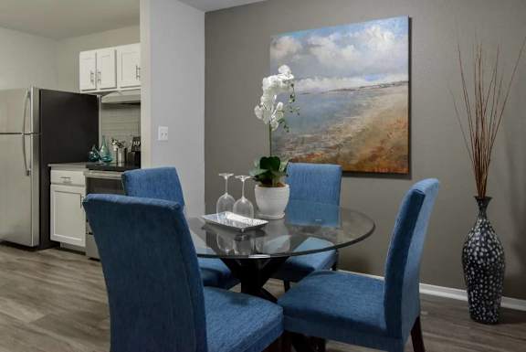 A dining room with a glass table and blue chairs.