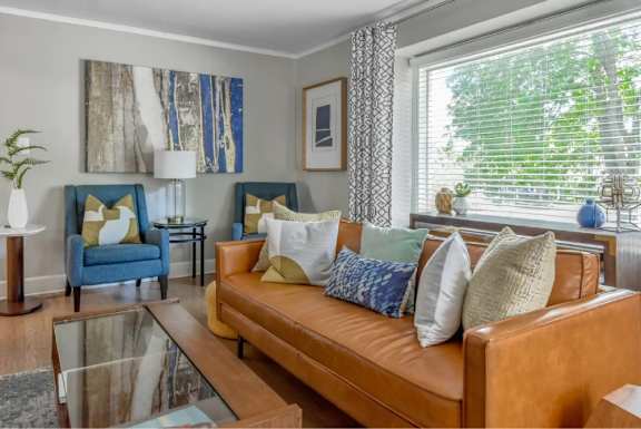 A living room with a brown leather couch and a blue chair.