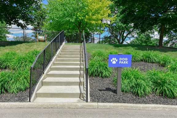 A set of stairs leads to a park with a blue sign.