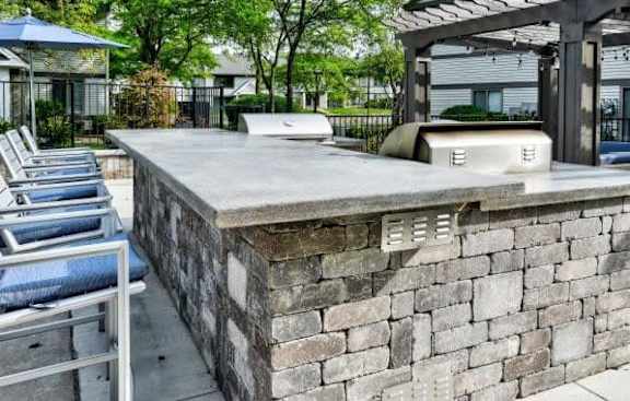 A concrete patio with a stone wall and a bench.