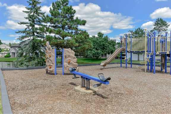 A playground with a slide, swings, and a seesaw.