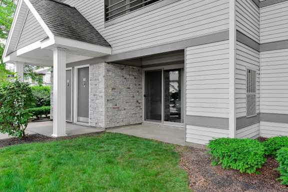A house with a grey siding and a stone pillar.