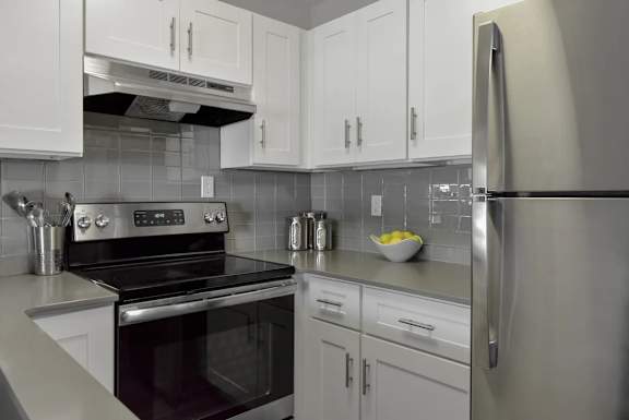 A modern kitchen with a stove, refrigerator, and cabinets.
