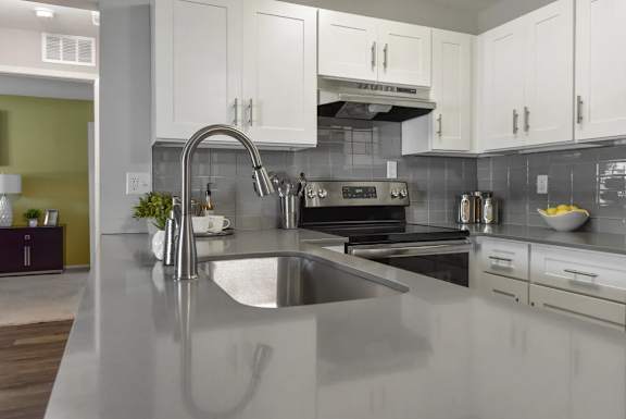 A modern kitchen with a stainless steel sink and white cabinets.