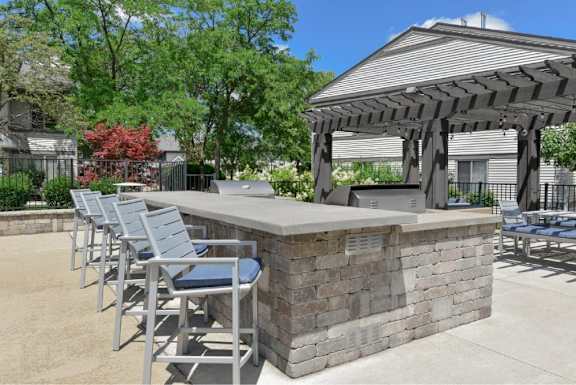 A patio with a bar and chairs under a pergola.