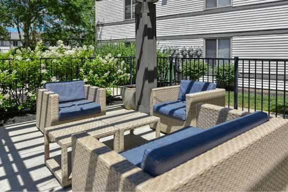 A patio with a wicker chair and a blue cushion.