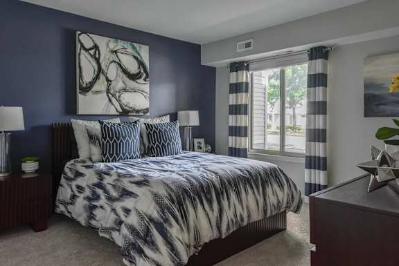 A bedroom with a large bed and a painting on the wall.