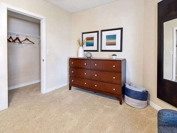 A room with a wooden chest of drawers and two pictures on the wall.