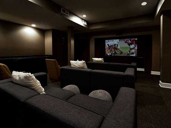 A dark room with a couch and a television playing a football game.